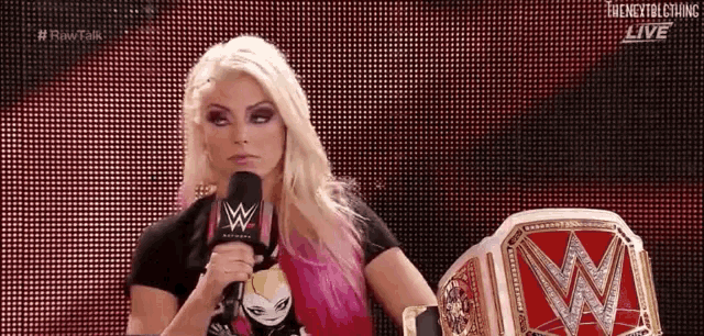 a woman is holding a microphone in front of a wrestling ring .