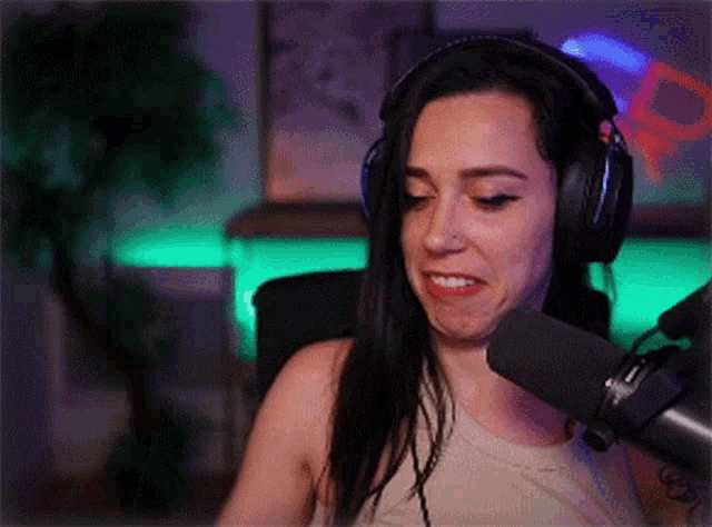a woman wearing headphones is talking into a microphone and making a funny face .