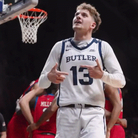 a basketball player wearing a butler jersey looks up at the net