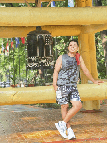 a man stands in front of a large bell that says world peace bell on it