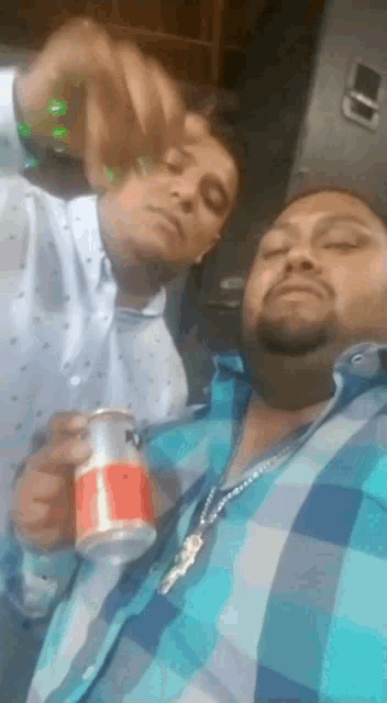 a man in a plaid shirt is holding a coca cola can next to another man