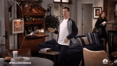 a man is standing in a living room with a couch and a table .