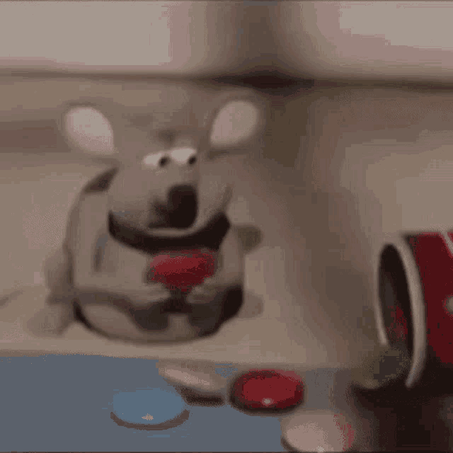 a stuffed mouse is eating a red apple next to a bucket of buttons .