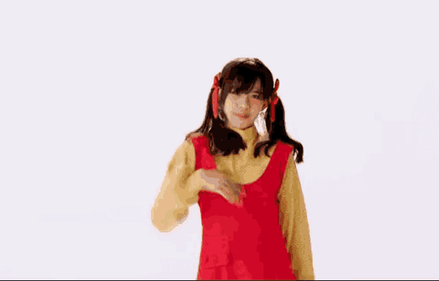the girl is wearing a red dress and a yellow sweater and is dancing .