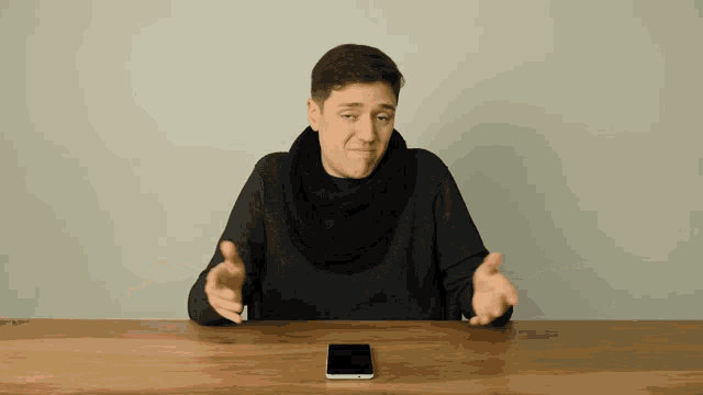 a man sitting at a table with a phone on it