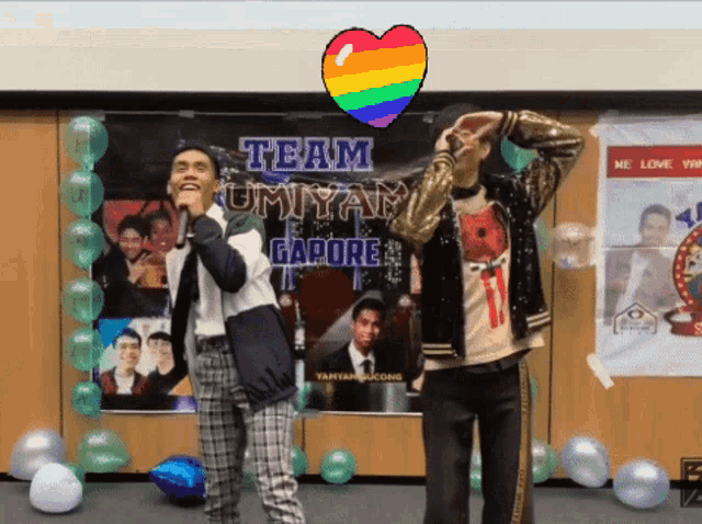 two men are singing in front of a sign that says team umiyam gapore