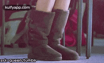 a woman wearing a pair of ugg boots is standing in front of a chair .