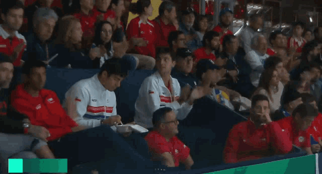a group of people sitting in a stadium with one wearing a jacket that says ntv on it