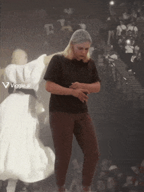 a woman in a black shirt is dancing in front of a crowd with a viggle.ai logo