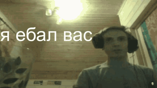 a man wearing headphones stands in front of a wall that says " ebal bac "