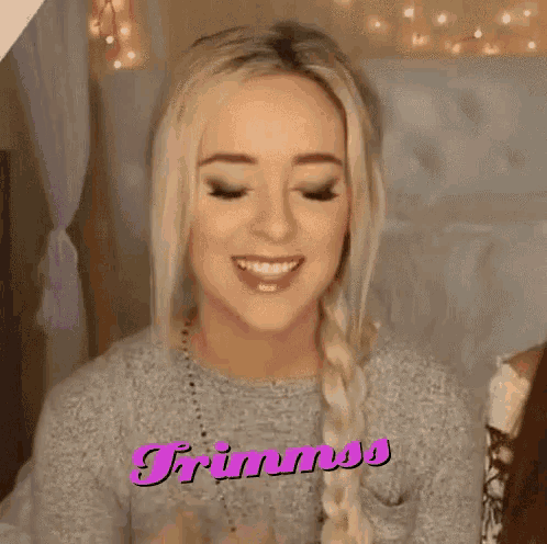 a woman in a gray sweater is smiling and the word trimmos is on the bottom right