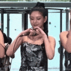 a woman in a strapless dress is holding a microphone and making a heart with her hands .