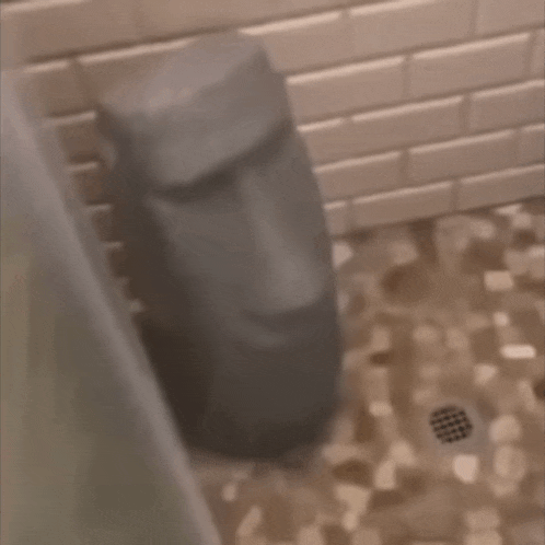 a statue of a face is sitting on a tiled floor in a bathroom