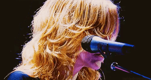 a woman singing into a sennheiser microphone in a pixelated image