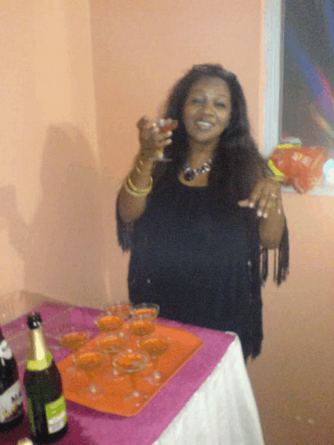 a woman stands in front of a table with glasses and a bottle of moet