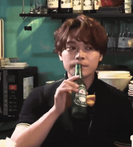 a man is drinking from a bottle of heineken