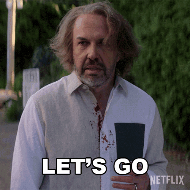 a man with blood on his shirt is holding a book and says let 's go netflix