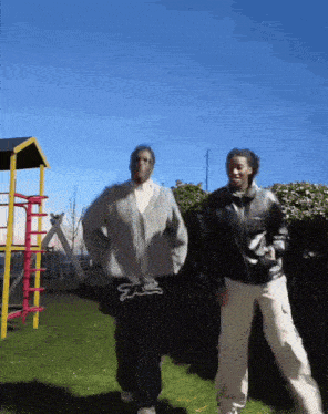 two men are dancing in front of a playground with one wearing a sweater that says ' ea ' on it