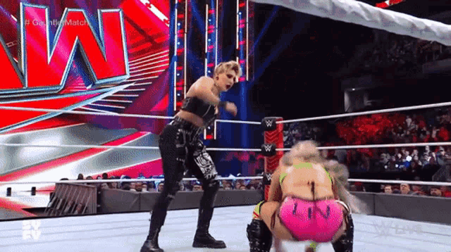 two women are wrestling in a wrestling ring and one of them has the number 1 on her shorts