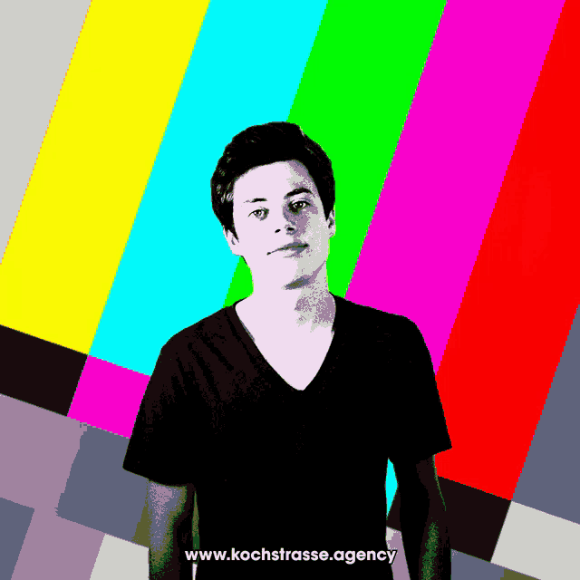a young man stands in front of a colorful background with the website www.kochstrasse.agency written below him