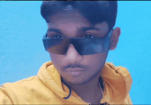 a young man wearing sunglasses and a yellow sweatshirt
