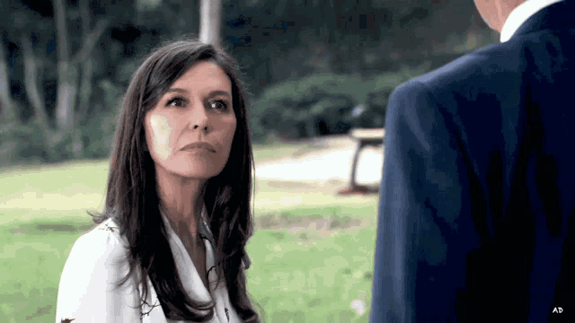 a woman in a white shirt and a man in a suit are looking at each other