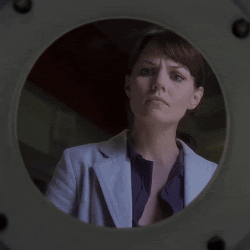 a woman in a lab coat is looking through a hole