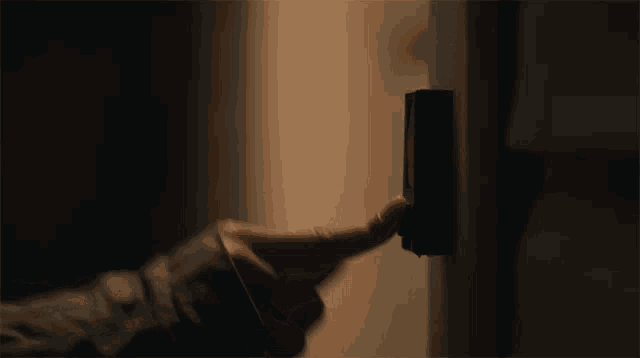 a person 's hand is pressing a button on a wall