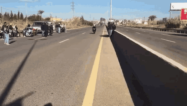 a group of people are standing on the side of a highway next to motorcycles