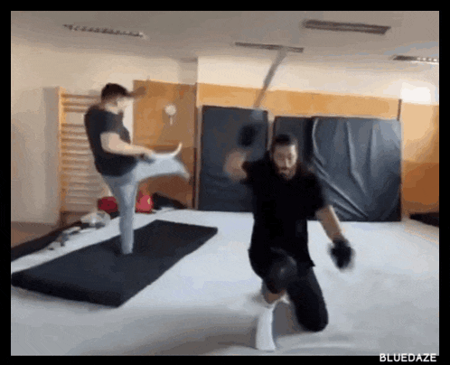 a man kicking another man with a sword in a gym with the words bluedaze on the bottom right