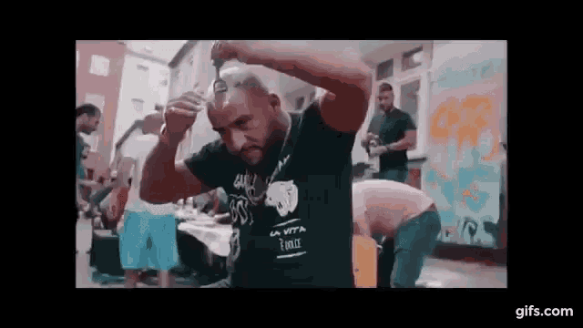 a man is cutting his hair with a pair of scissors while a group of people watch .