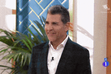 a man in a suit and white shirt is smiling in front of a sign that says late afternoon