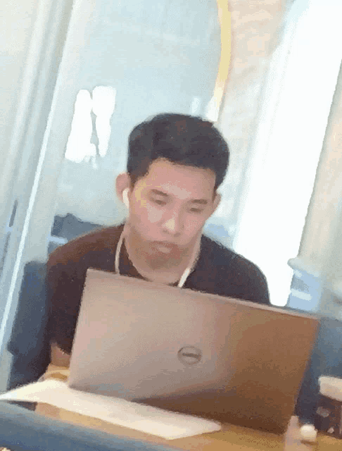 a man wearing ear buds looks at a dell laptop