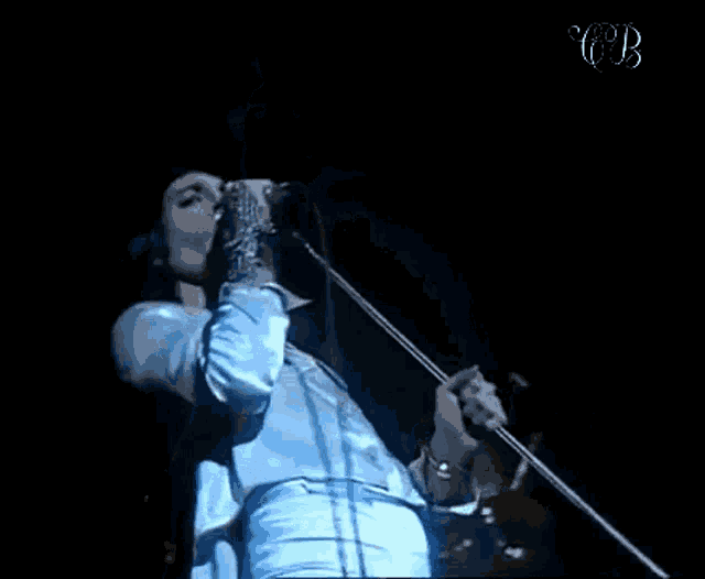 a man is singing into a microphone on a stage in a dark room .