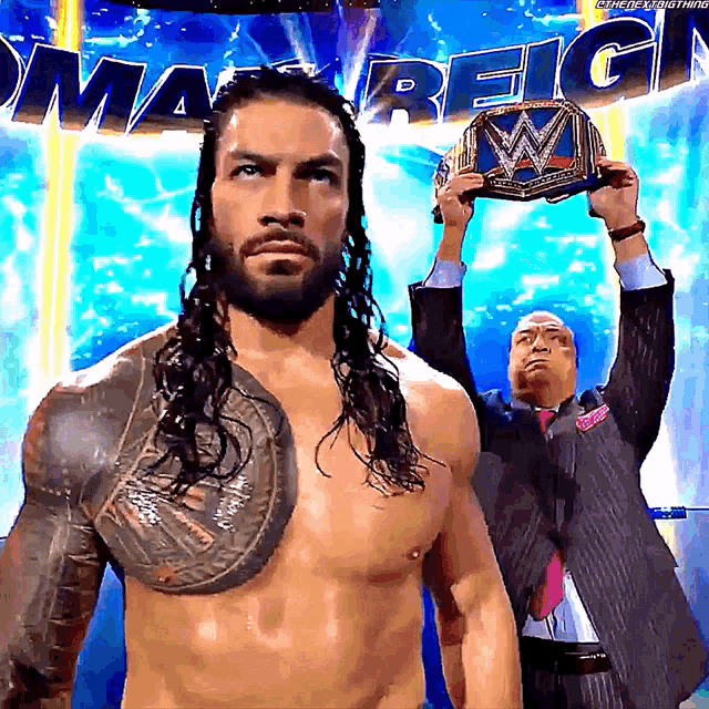 a man in a suit is holding up a wrestling championship belt