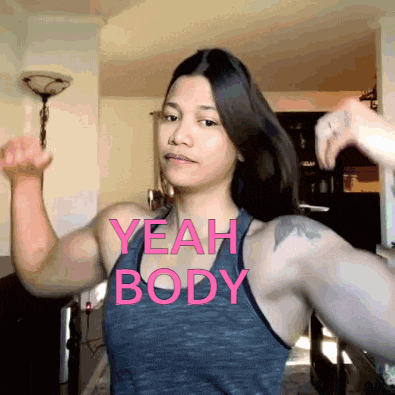 a woman flexes her muscles with the words yeah body written on her chest