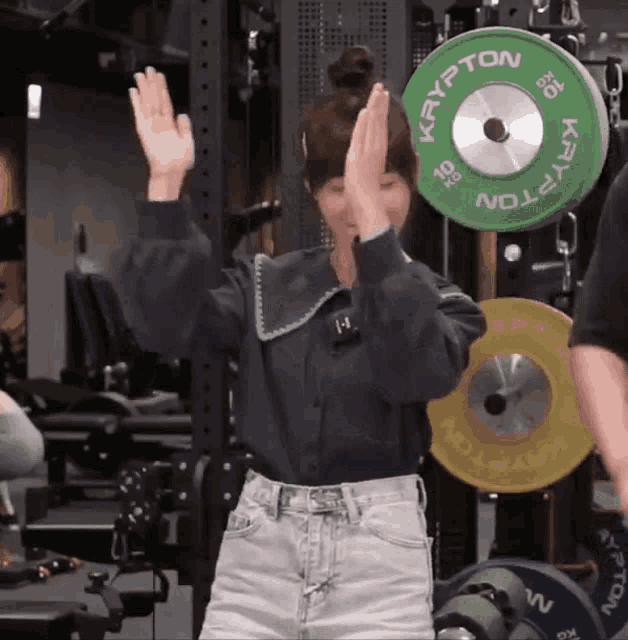 a woman standing in front of a green krypton barbell