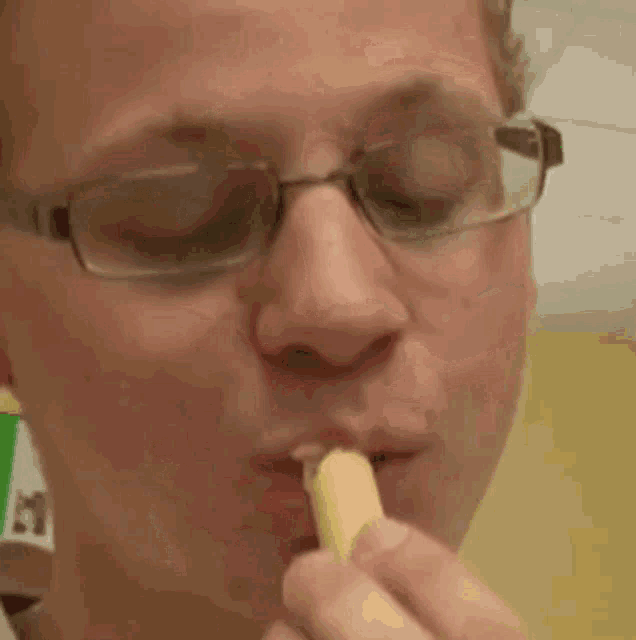 a man wearing glasses is eating a banana .