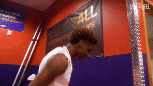 a basketball player is standing in front of a banner that says basketball