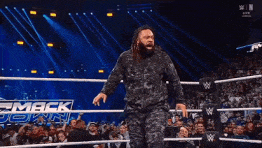 a wrestler with dreadlocks is standing in a wrestling ring .