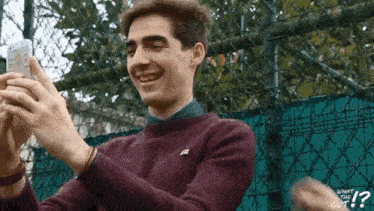 a man in a maroon sweater is taking a picture of himself with his phone
