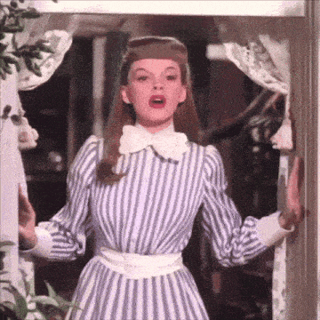 a woman in a striped dress is standing in front of a window and making a funny face .
