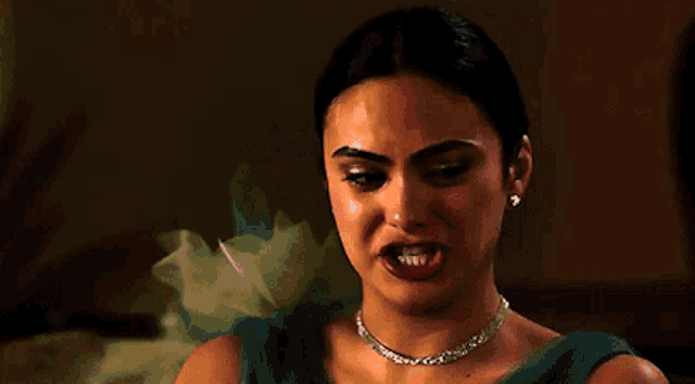 a woman wearing a necklace and earrings is making a funny face .