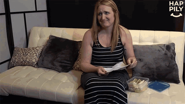 a woman is sitting on a couch holding a piece of paper with hap pily written on the bottom