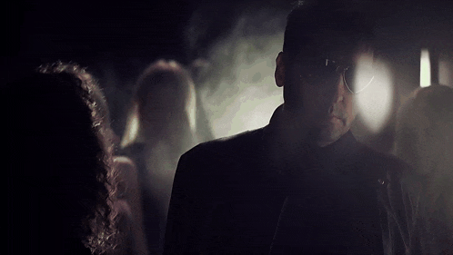 a man in a dark room with a woman in the foreground
