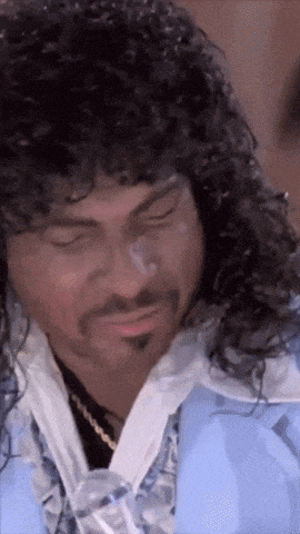 a man with curly hair and a beard wearing a blue shirt