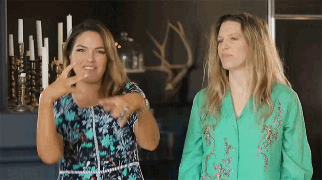 two women are standing next to each other and one is wearing a green shirt with flowers on it