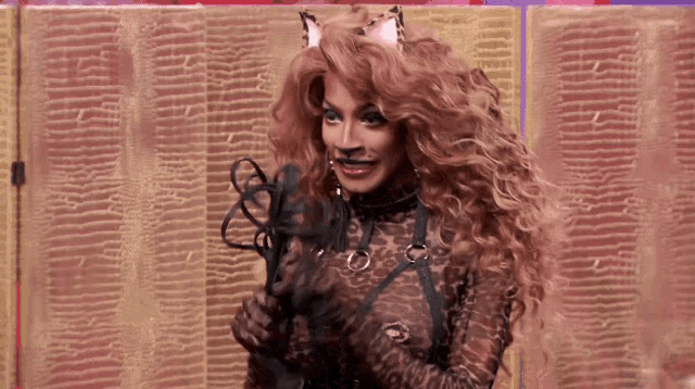 a woman in a cat costume is holding a whip in her hands .