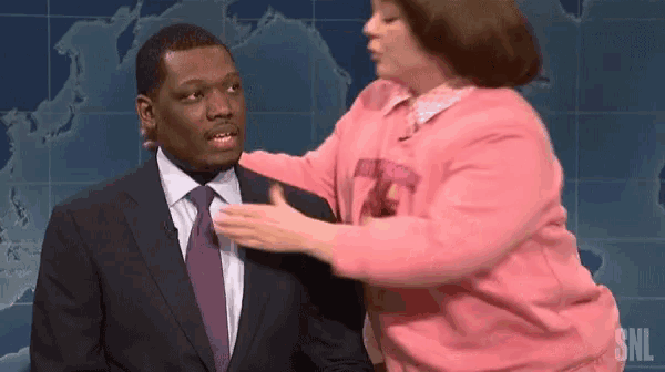 a woman in a pink sweater is putting her hand on a man 's chest .