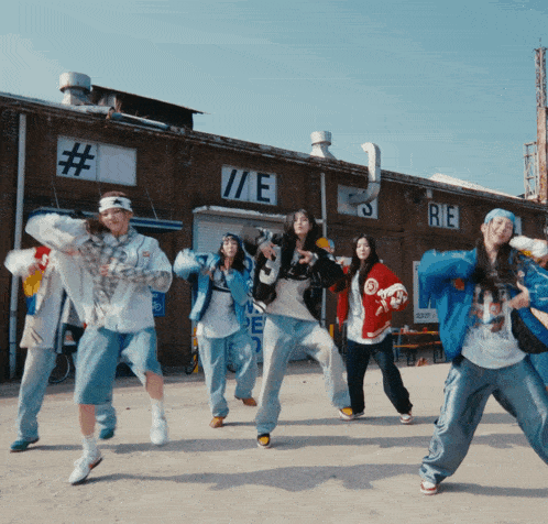 a group of young people are dancing in front of a building that says re